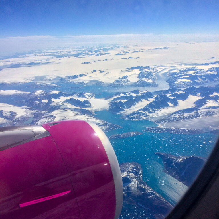 pink plane engine over blue landscape from airplane booking cheap flights