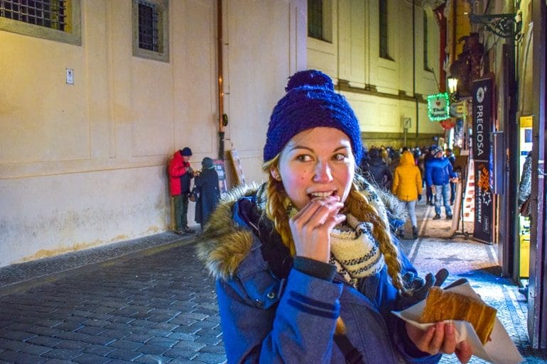 Frau in blauer Jacke und Mütze isst Nachtisch in Prag