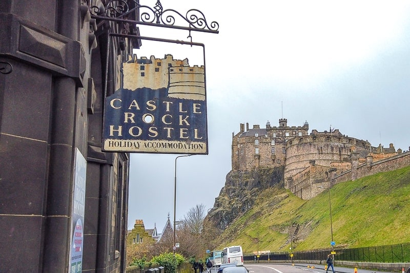 Hostelschild hängt im Vordergrund mit Schloss von Edinburgh dahinter