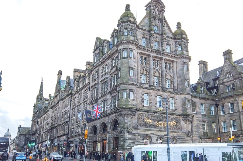 old hotel building with flags flying out front by busy edinburgh street