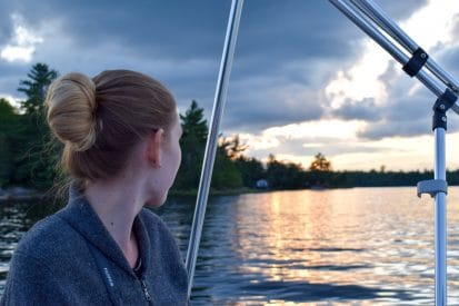 girl sitting in boat looking at blue lake with sunset