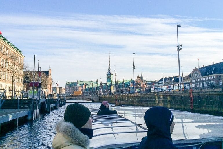 Menschen mit Mützen auf Flachboot in Kanal in Kopenhagen Dänemark