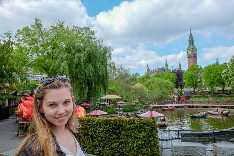 girl in front of lake with trees and tower behind at tivoli gardens
