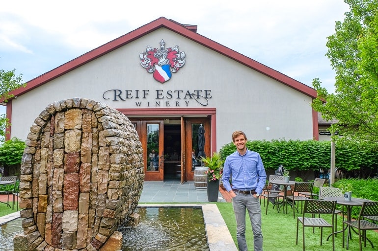 man standing beside fountain in front of winery entrance reif estates