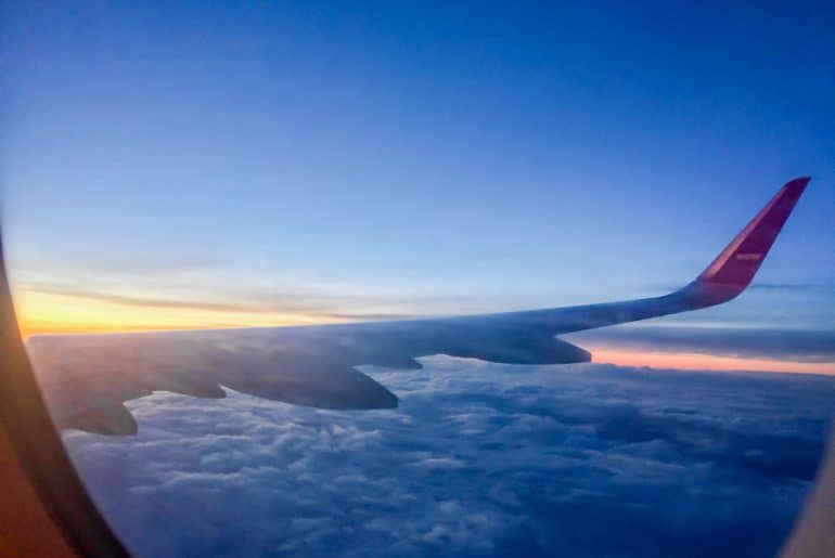 airplane wing with blue clouds and sunrise