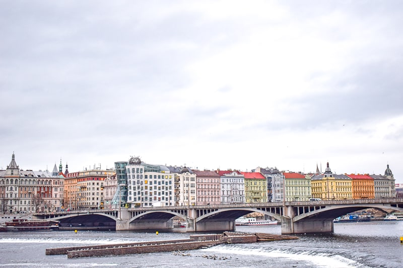 famous dancing house building in prague with river and bridge in front