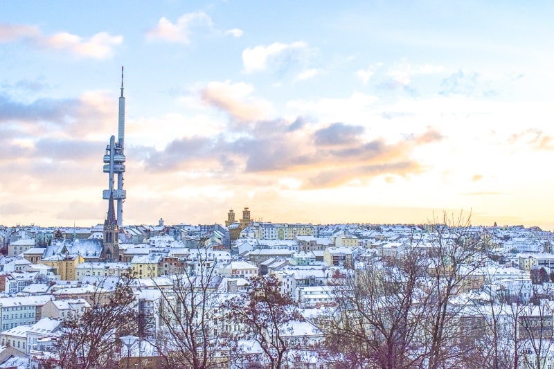 Hoher Fernsehturm in Prag mit schneebedeckten Dächern herum