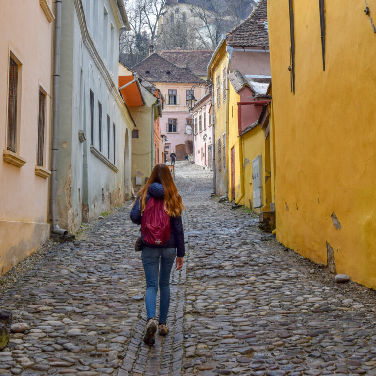 girl with daypack backpack walking though old town