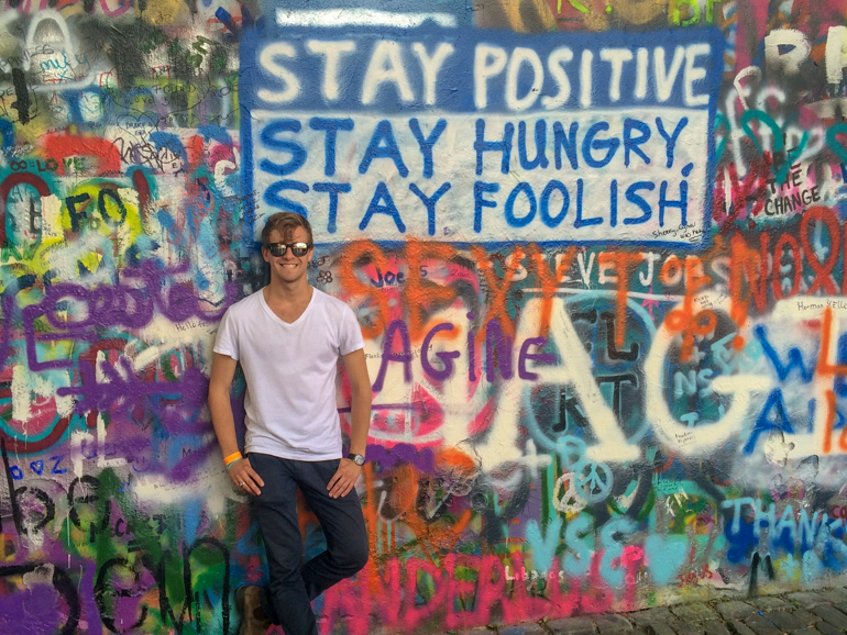 guy standing up against graffiti wall in prague on europe trip itinerary