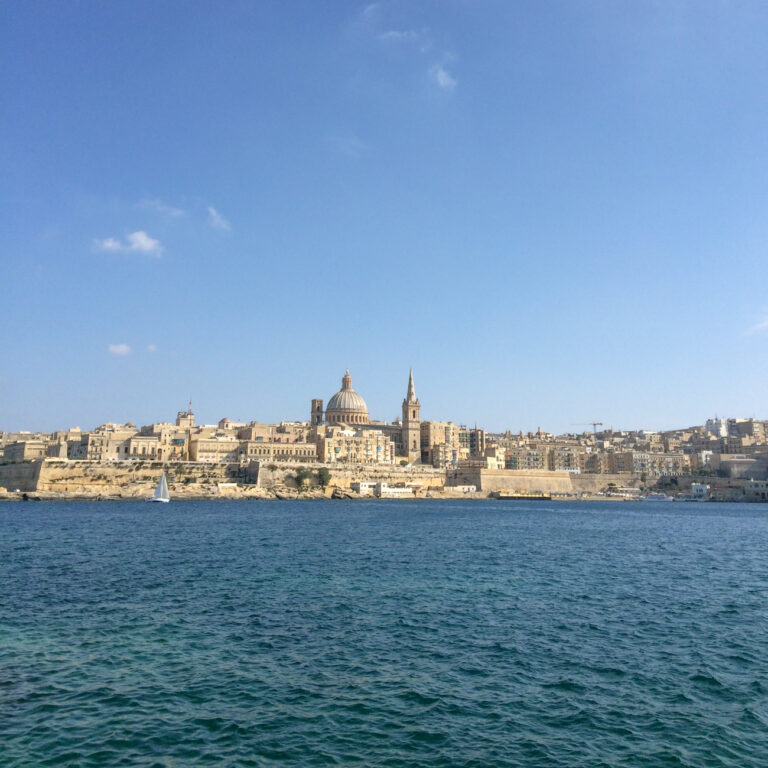 dome of church in valletta malta with blue sky and water