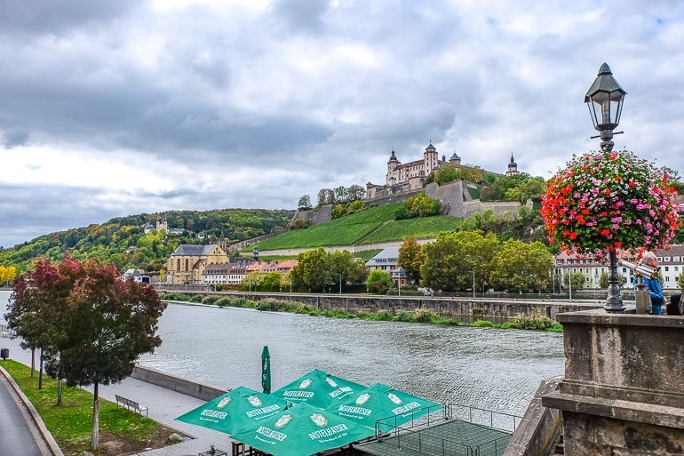 castle on hill with river below and green umbrellas in wurzburg germany