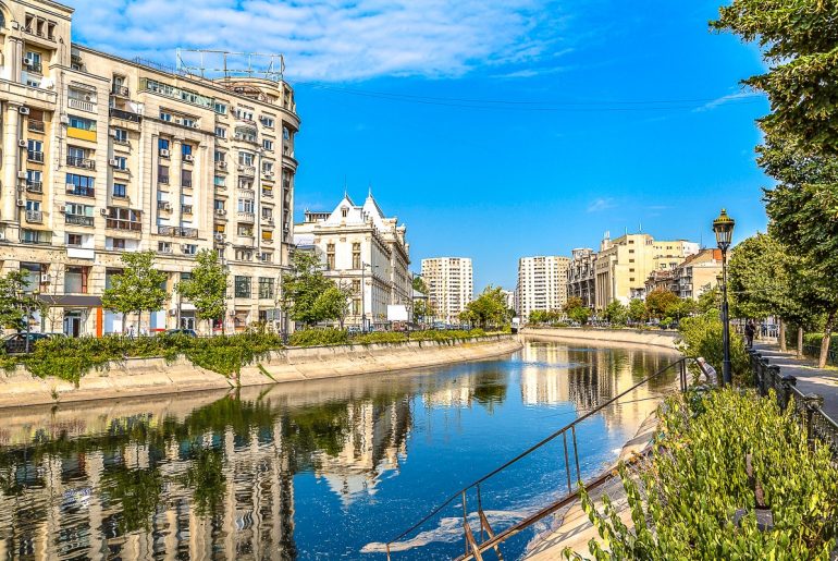 old apartment buildings with blue river flowing in front where to stay in bucharest
