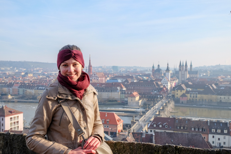 Frau schaut in Kamera mit Gebäuden von Würzburg in Hintergrund