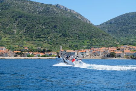 boat making waves with croatian island in background