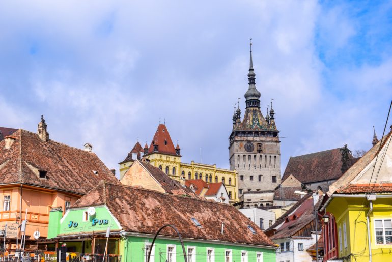 colourful houses and tower in romania with blue sky day trips from brasov
