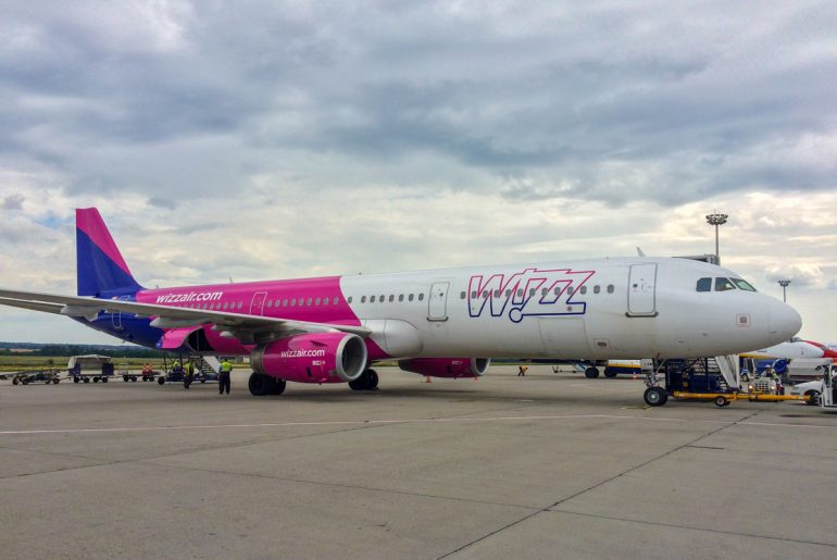 pink and white wizz air airplane on runway