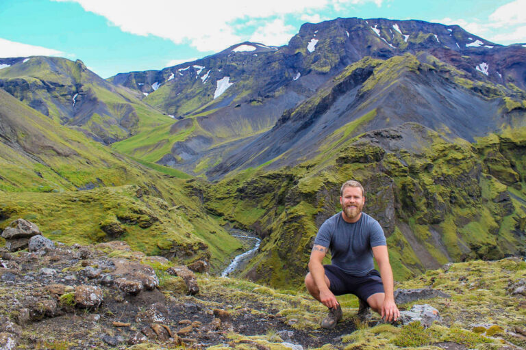 icelandic man kneeling with mountains in back background planning a trip to iceland