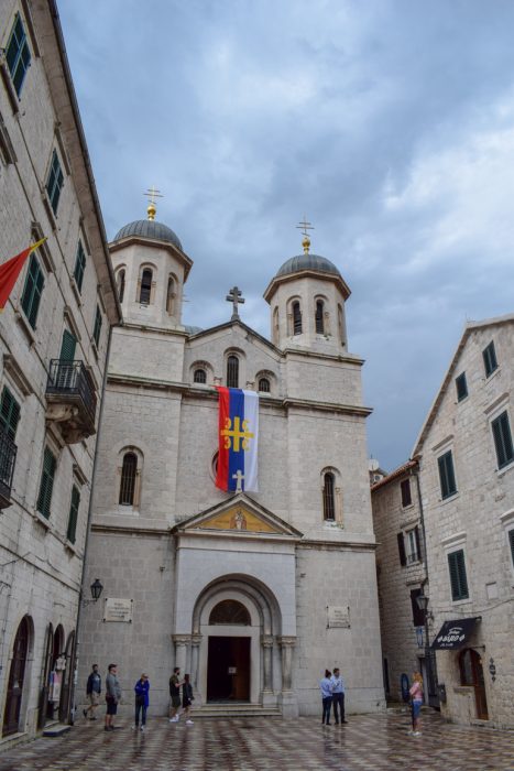 stone church with flag and dome towers in old town kotor.