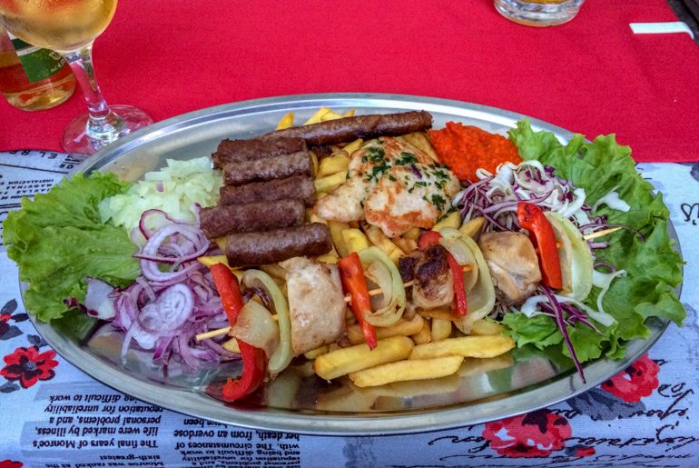 grilled meat platter with fried and vegetables in red table cloth in mostar bosnia