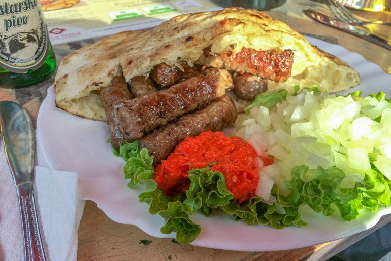 sausages with red sauce in pita bread on white plate in mostar