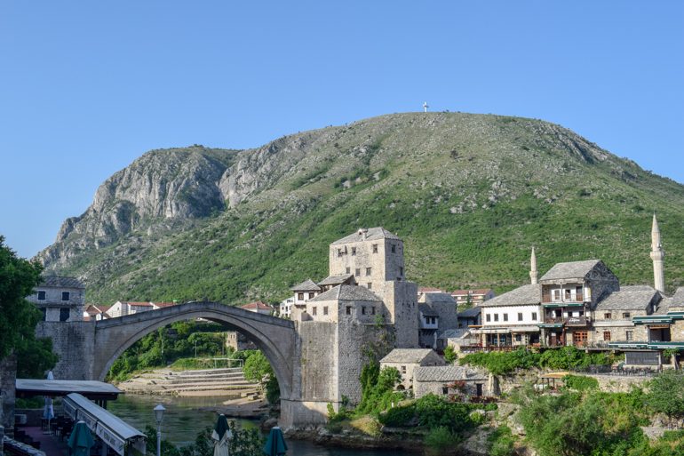 old town bridge in mostar with sun rising and mountain in background