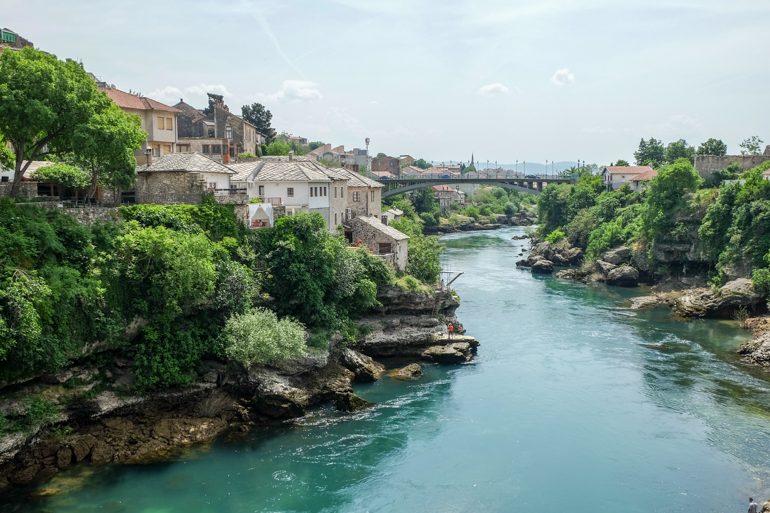 blue neretva river in mostar bosnia with old houses and blue sky