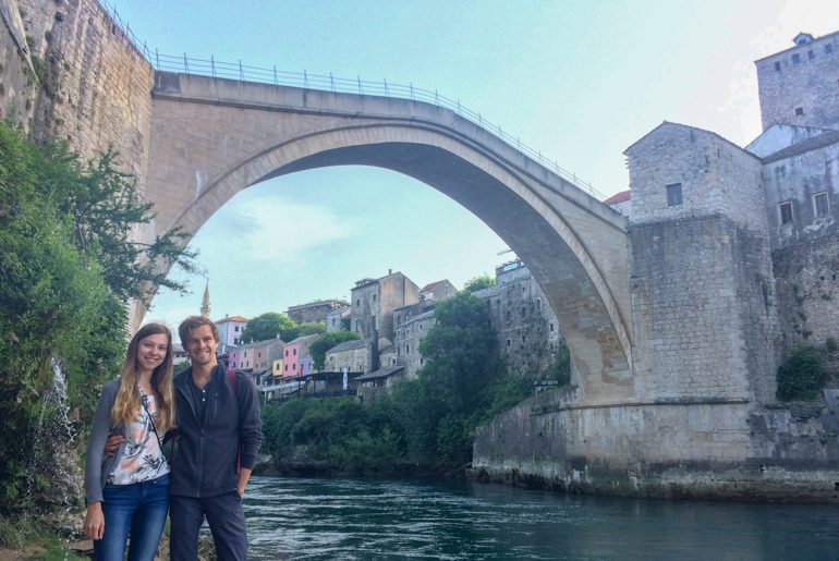 young couple posing under old bridge in mostar with river behind things to do in mostar