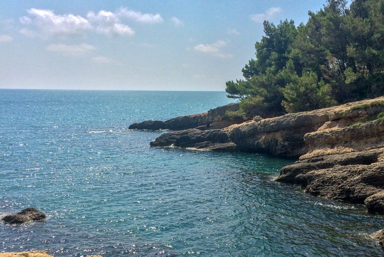 blue water with rocks and green trees in cove things to do in ulcinj