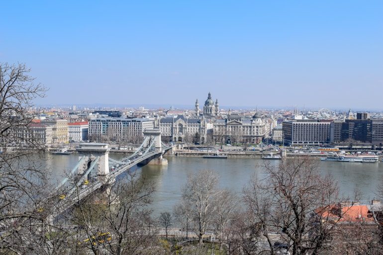 cathedral and chain bridge through trees in budapest best areas to stay