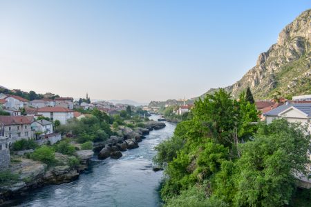blue river with green trees and old houses on river bank in mostar bosnia and herzegovina travel