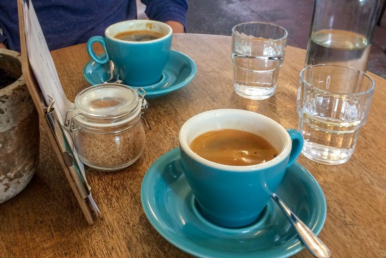 blue mugs and water glasses with menu on wooden table in coffee shop in edinburgh