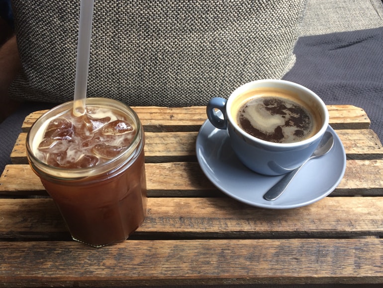 cold coffee in glass and coffee in blue mug on wooden crate in milkman coffee shops edinburgh