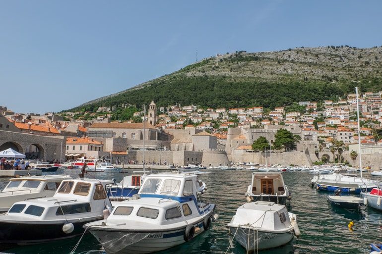 boats in dubrovnik harbour with hill in behind on croatia road trip