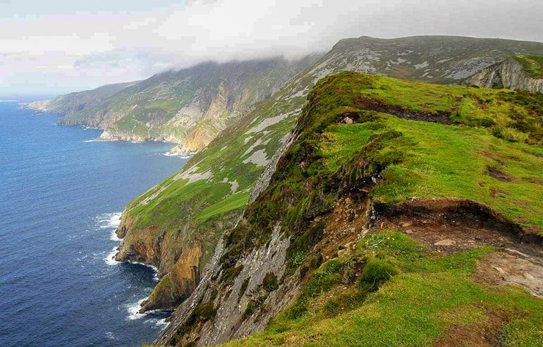 green rocky cliffs with blue water below slieve league cliffs ireland travel tips