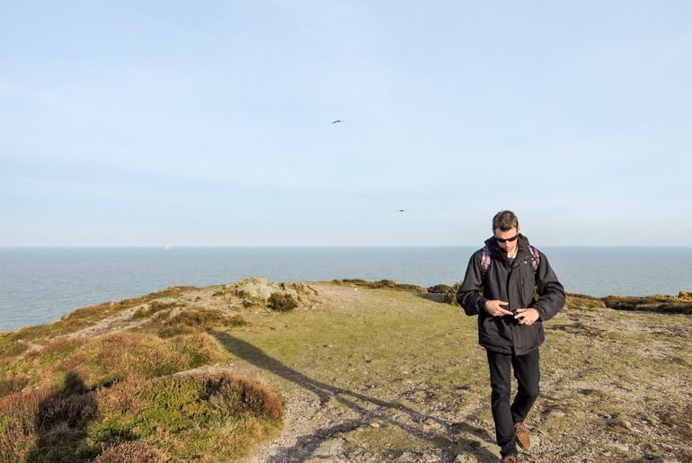 Mann mit schwarzer Jacke läuft weg von Klippe Irland Sehenswürdigkeit