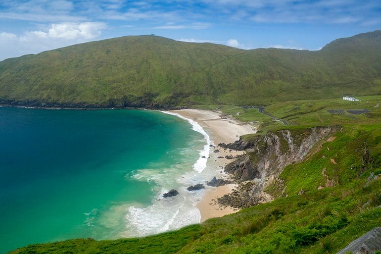 blue water waves and white sand in green bay ireland travel tips