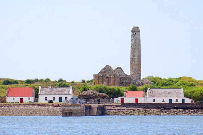 brich chimney and small colourful houses on scattery island with water in front ireland travel tips