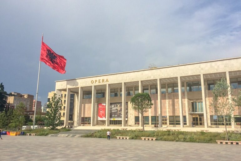 opera house with red albanian flag on pole places to visit in tirana