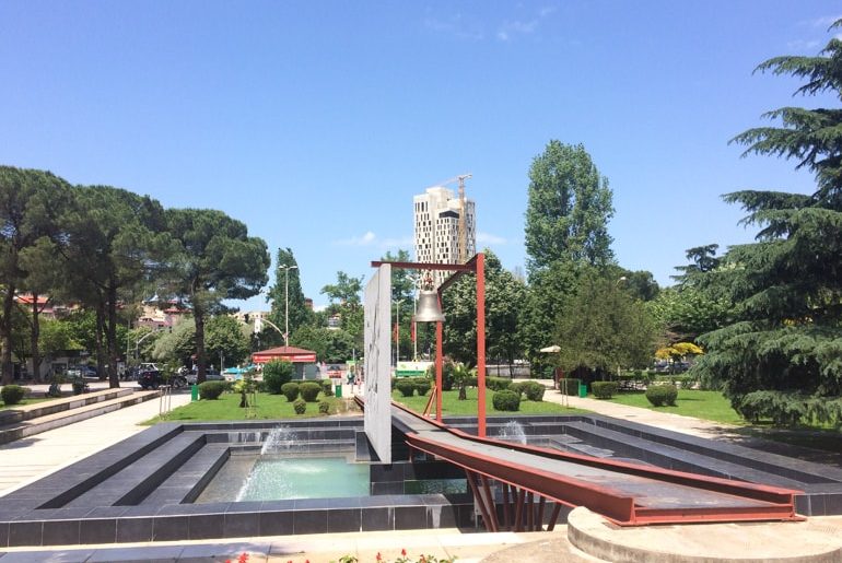 bell monument with fountain under in green park places to visit in tirana