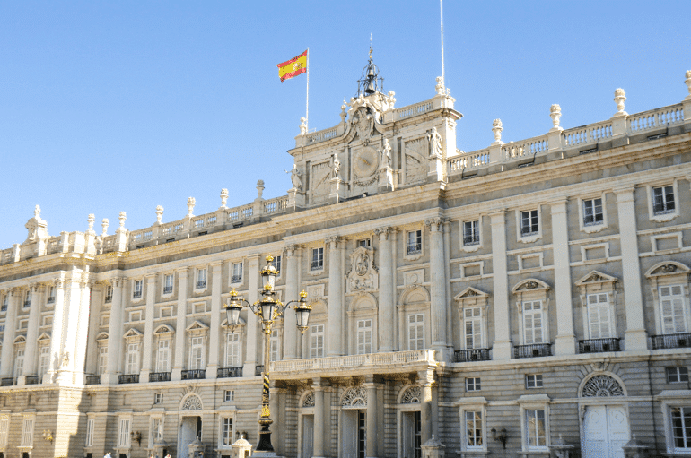 Weißer Königspalast Madrid mit spanischer Fahne und blauem Himmel