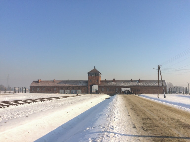red brick building in field with snow covered roads at auschwitz