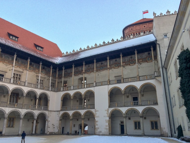 interior courtyard of castle with arched walkways and polish flag on top wawel castle 3 days in krakow