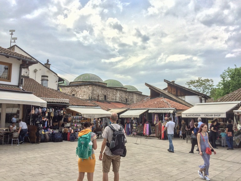 man and woman with backpacks in turkish market sarajevo best restaurants in sarajevo