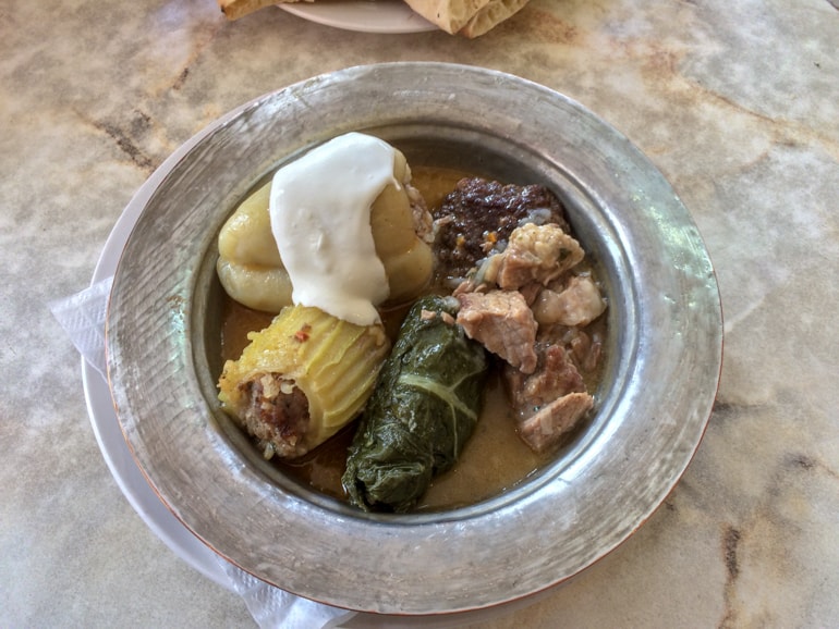 Metallschüssel mit bosnischem Essen auf Tisch Restaurants Sarajevo