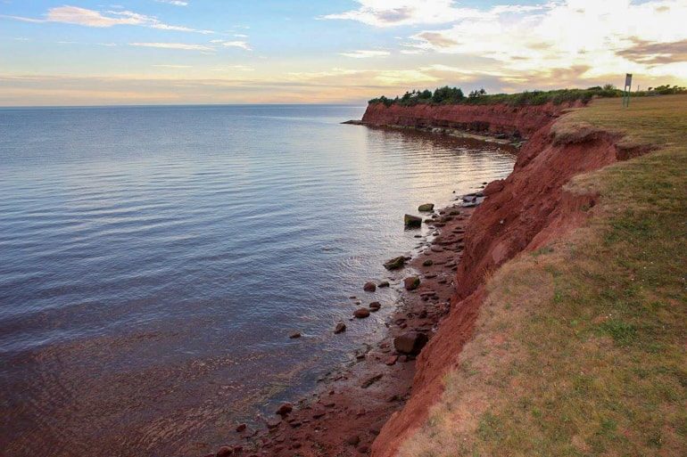 red sand cliffs with green grass canada sightseeing