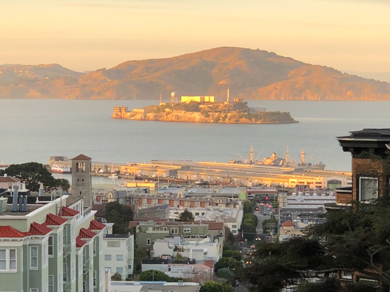 Alcatraz island in distance looking down san francisco street in golden sunshine insider tips