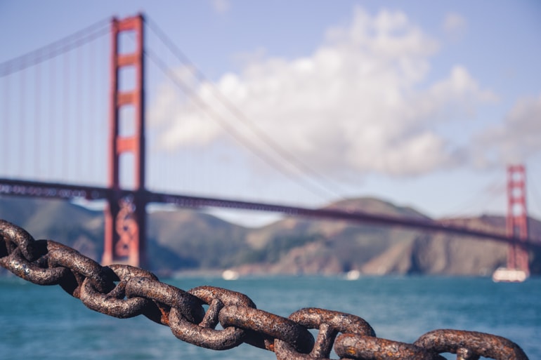 orange golden gate bridge far in distance with rusted chain in foreground san francisco insider tips