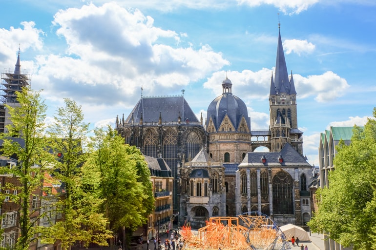 aachen cathedral with green trees and public square in foreground.