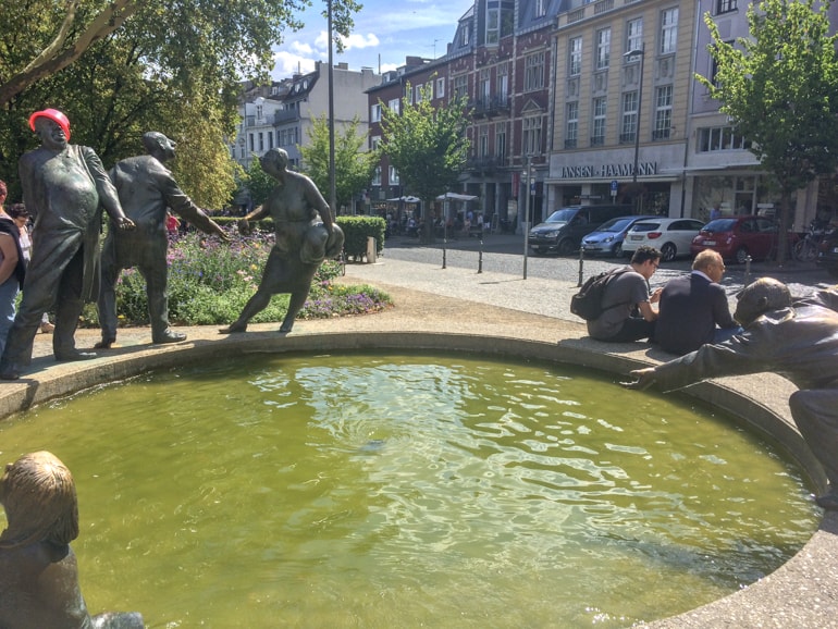 green water fountain with statues around in city.