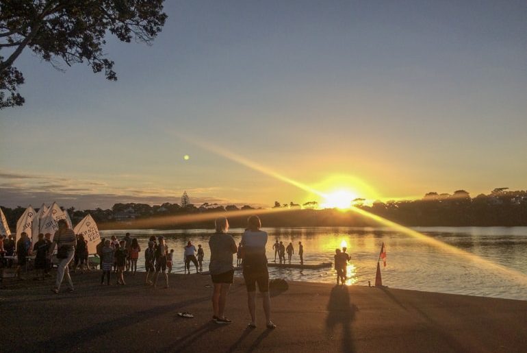Sonnenuntergang am Strand mit Menschen und gelber Sonne Neuseeland Sehenswürdigkeiten